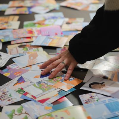 A hand resting on a number of small artworks displayed across a table